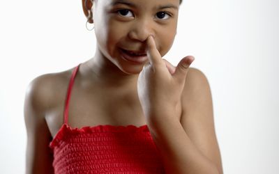 A little girl picking her nose