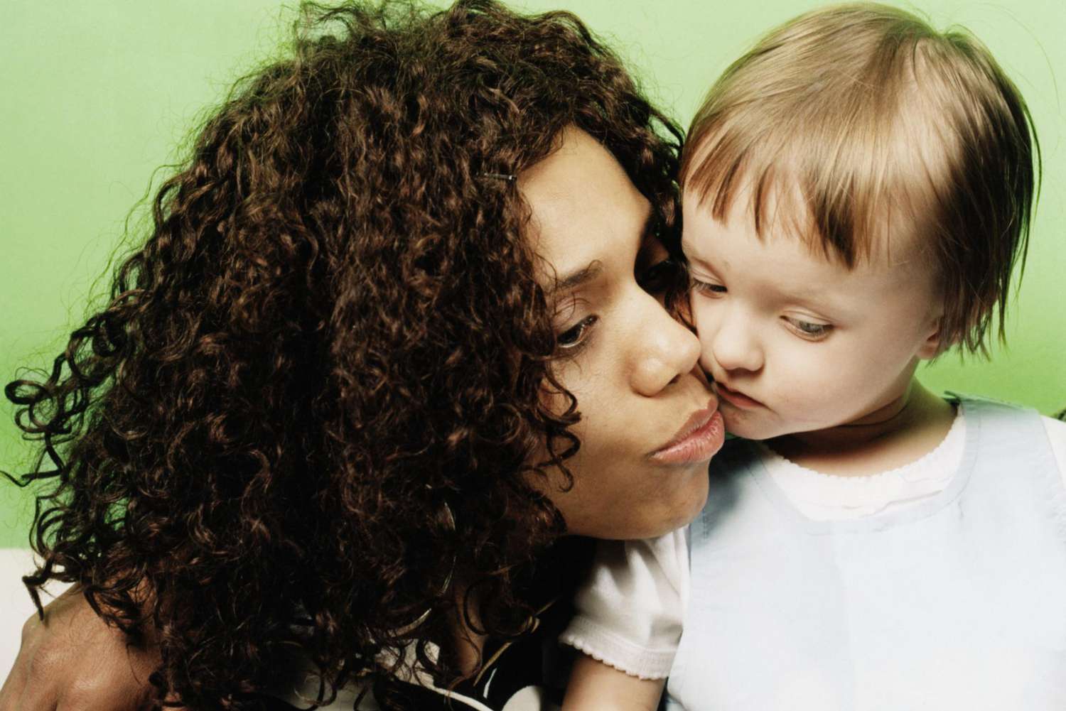 Woman embracing girl (2-4) indoors, close-up