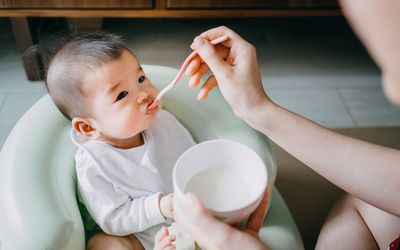 母亲第一次在家里用固体食物喂婴儿——库存照片