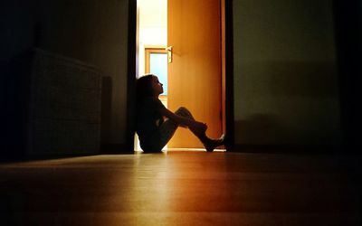 孩子坐在黑暗的房间门口