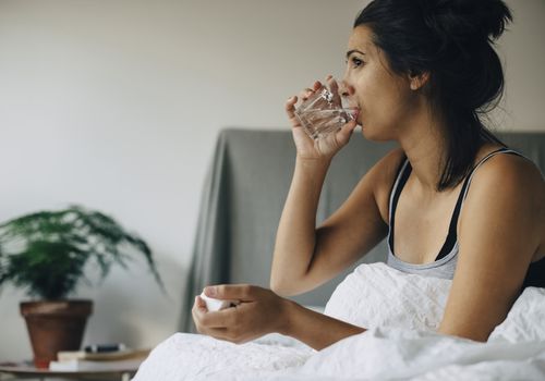 woman drinking water in bed