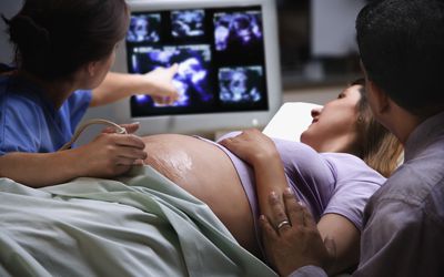 Female doctor pointing to ultrasound picture with pregnant woman