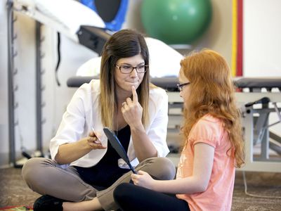 Young female speech therapist helping a young patient
