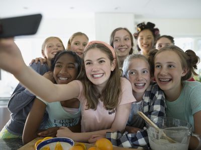 Girls taking a selfie while making breakfast after a slumber party
