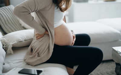 Cropped shot of pregnant woman touching her belly and lower back.