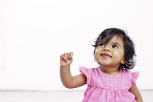 Baby girl in pink dress looking up
