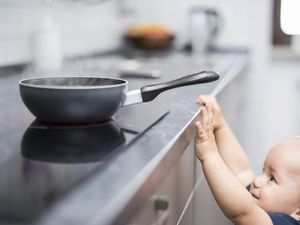 小男孩(1 y)试图够到炉子上的平底锅