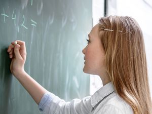 一名女学生在教室黑板上做数学题