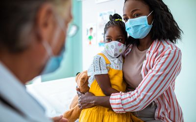 Mom and child wearing masks at pediatrician's office