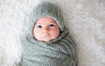Little newborn baby boy, swaddled in a knitted blanket