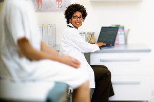 Female doctor talking to patient and using laptop in exam room, discussing IUI procedure
