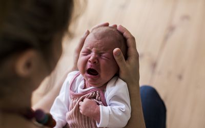 mom holding crying newborn