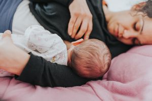 母亲在家里的床上哺乳新生儿的特写