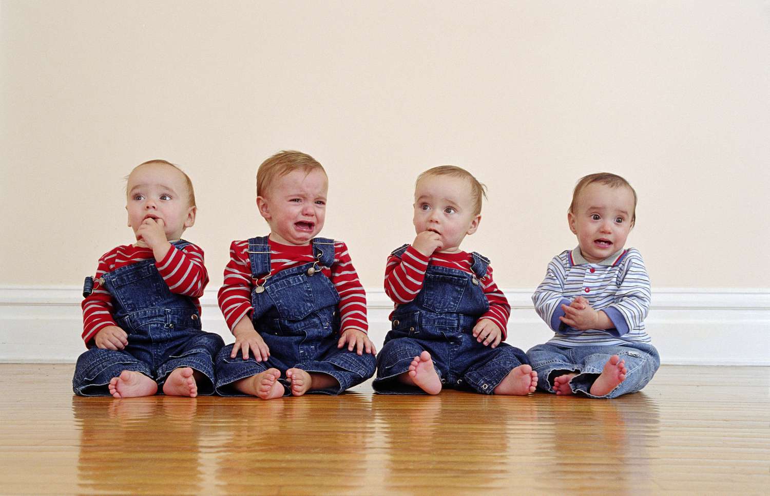 Quadruplets in overalls sitting in a row