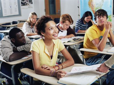 Teenage girl receiving graded homework in class, smiling