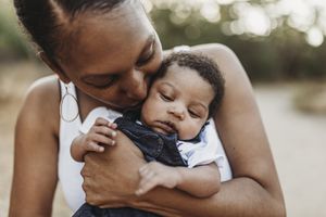 Black mother holding and kissing her baby