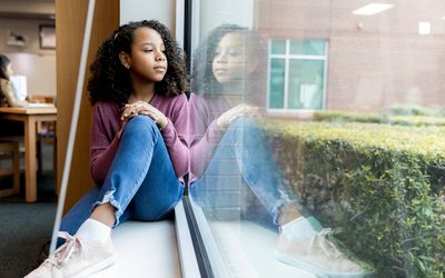 Young girl sitting on window ledge