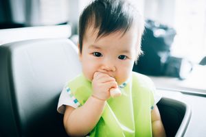 可爱的婴儿吃婴儿手指饼干在高椅子-股票照片