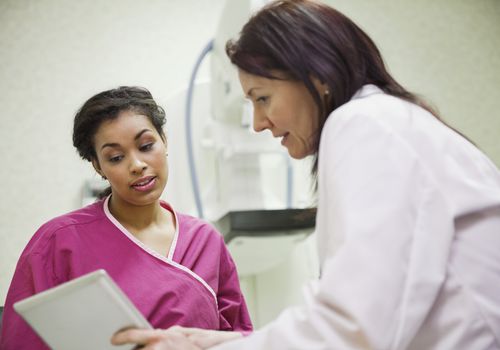 Mature doctor using digital tablet to explain to female patient