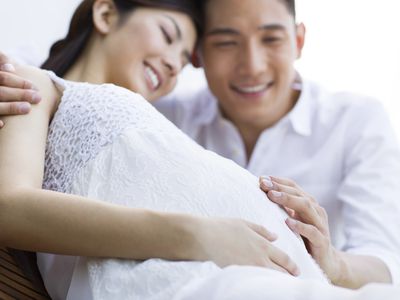 Pregnant woman with partner's hand on her belly