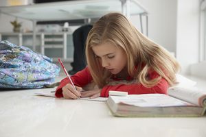 年轻女孩在家庭办公室的地板上做作业。