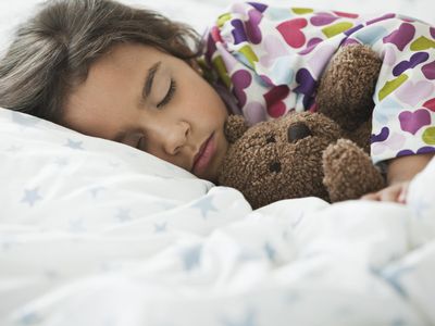 girl sleeping in bed with teddy bear