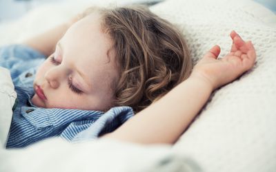 Sleeping male toddler with arms up on pillow