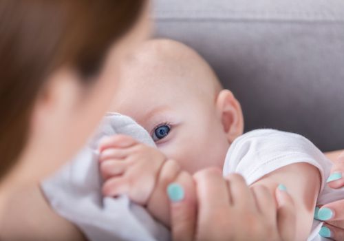Adorable blue eyed baby looks at mom while breastfeeding