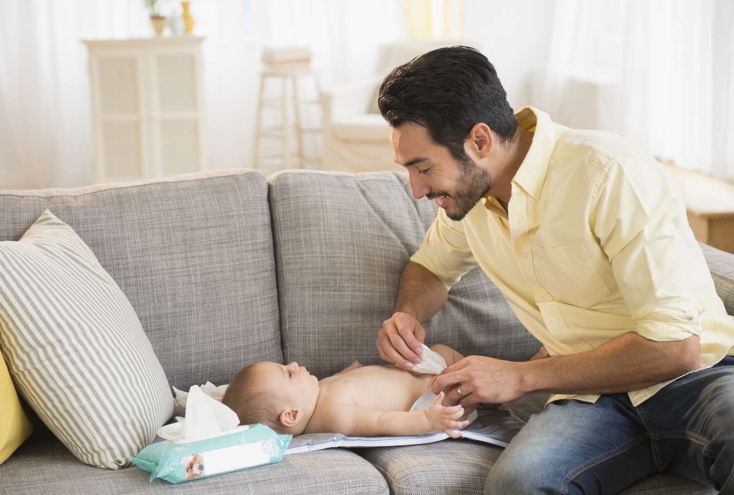 Father using baby wipes while changing his baby's diaper