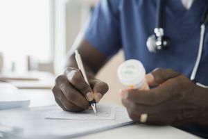 Close up of doctor with bottle writing prescription