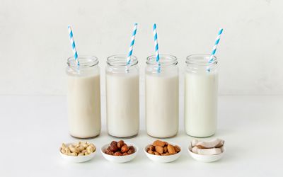 四罐非乳制品牛奶的小插图有蓝色和白色条纹吸管。