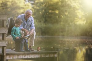 Grandfather and grandson reading at lake