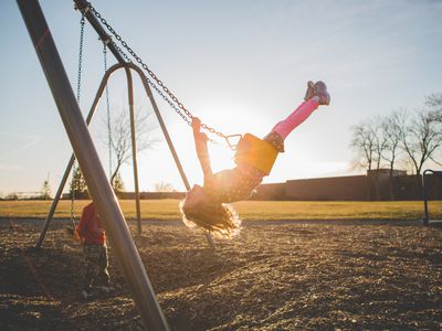 Girl swinging gleefully on a swingset.