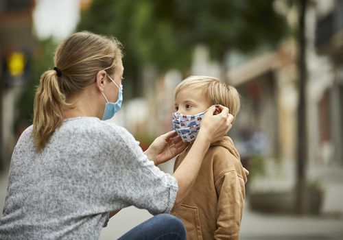 mom putting a mask on her young son