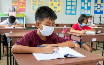 child wearing a face mask at a school desk