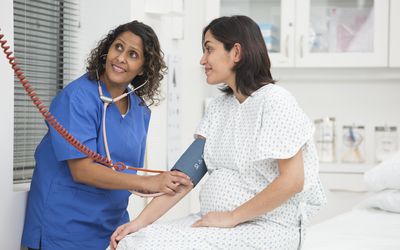 Mixed race nurse taking patient's blood pressure