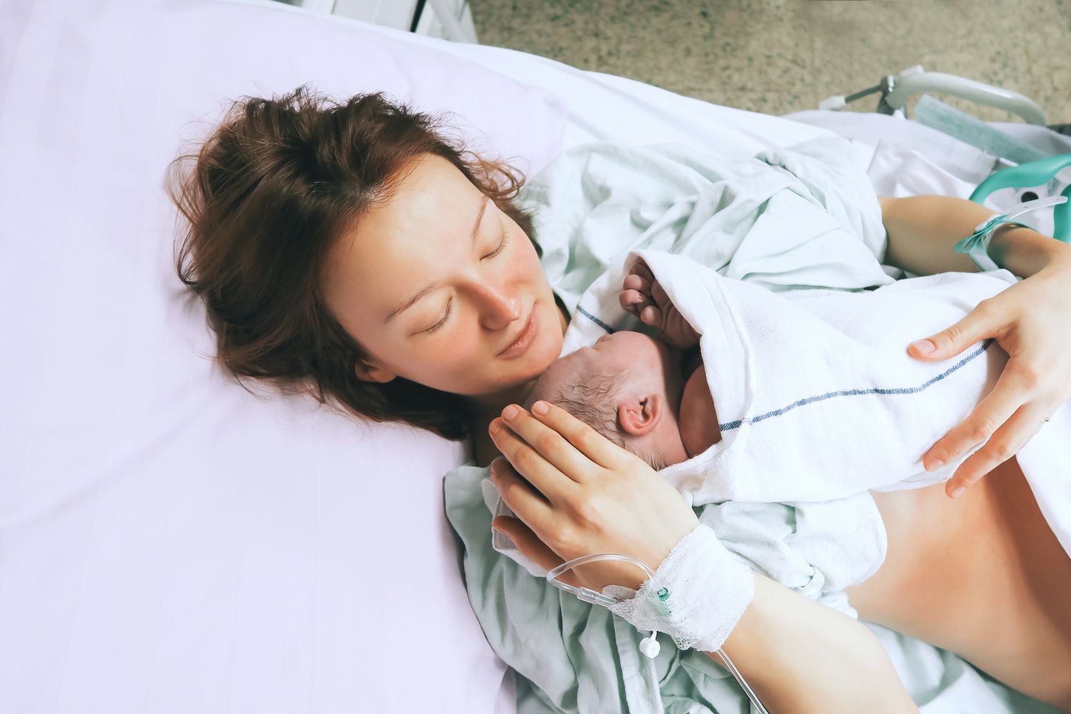 Woman holding newborn baby in hospital bed