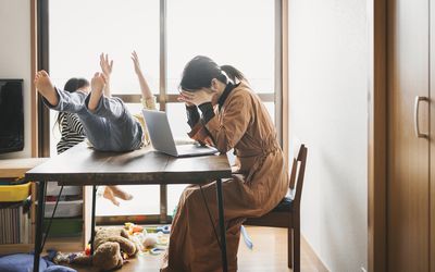 妈妈双手捧着头坐在厨房的桌子旁